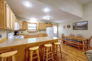 A kitchen with wooden cabinets, a white refrigerator, a stove, and a dining area with a wooden table and chairs.
