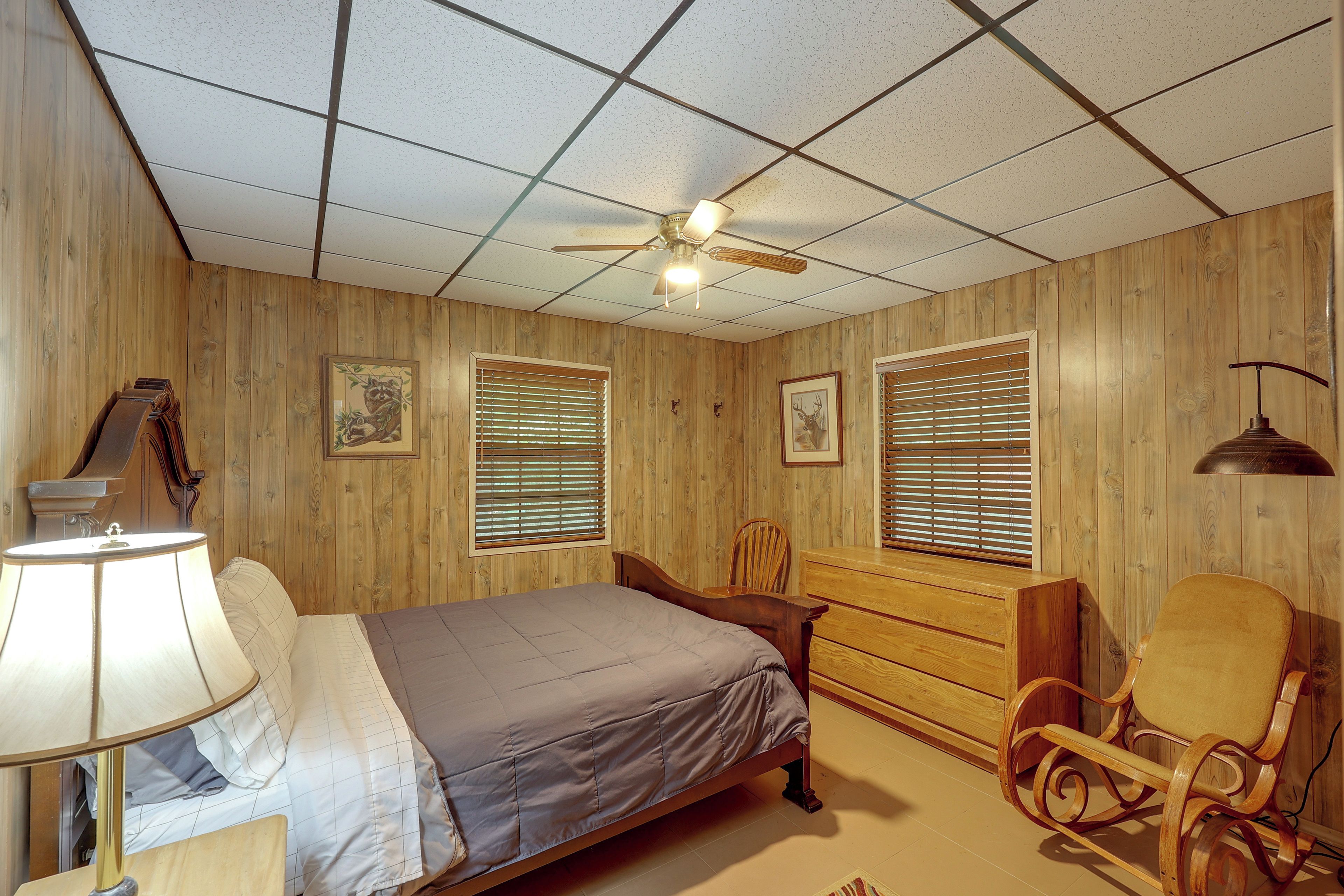 A bedroom with a bed, a chair, a desk, and a ceiling fan.