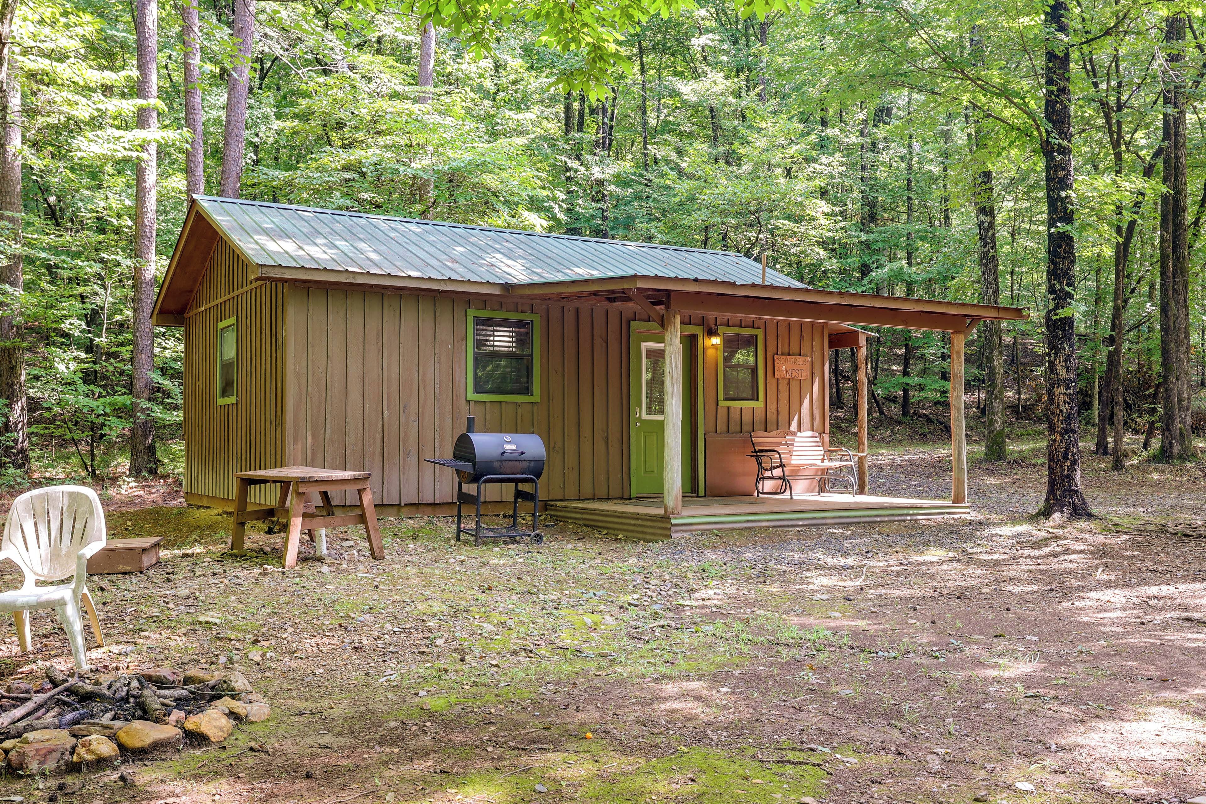 A rustic cabin with a porch, a grill, and a chair.