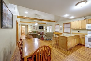 A spacious kitchen with wooden cabinets, a dining area with a wooden table and chairs, and a living room with a sofa and a television.