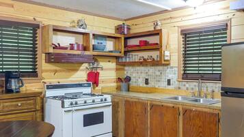 A compact kitchen with wooden cabinets, a stove, and a refrigerator.