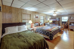 A bedroom with a large bed, a smaller bed, a desk, a chair, a bookshelf, and a staircase.