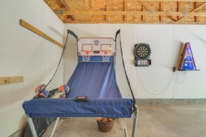 A room with a trampoline, a dartboard, and a bowling alley setup.