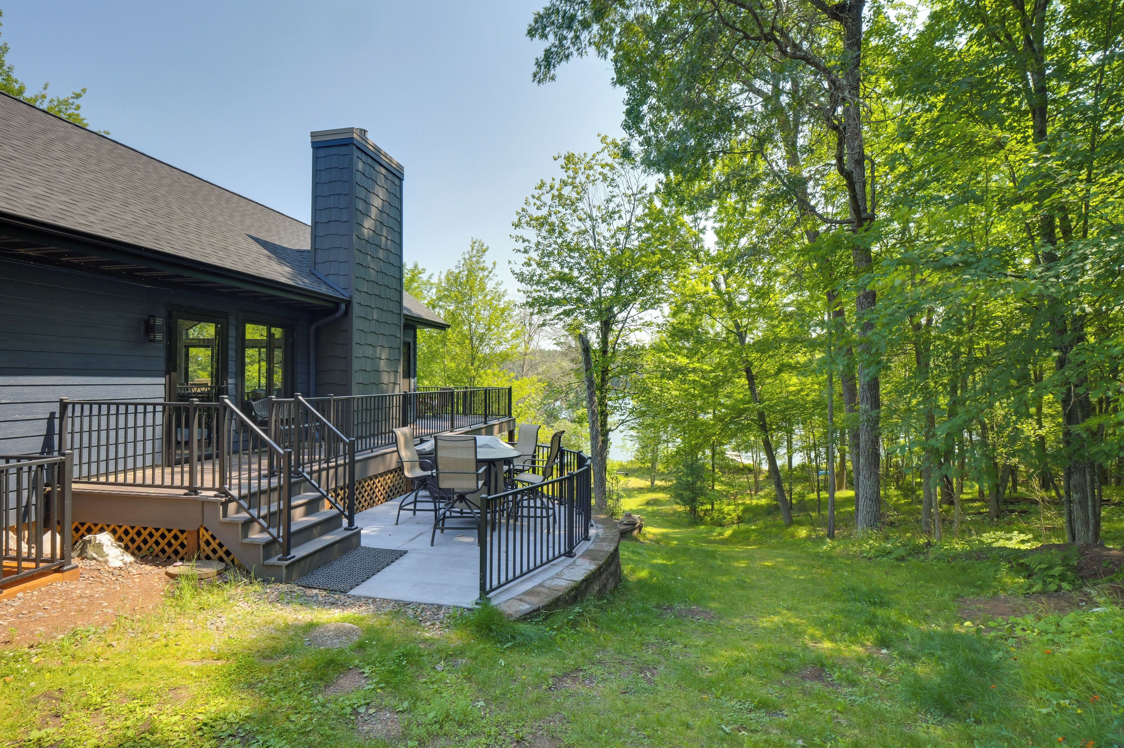 A house with a deck, outdoor furniture, and a view of a wooded area.