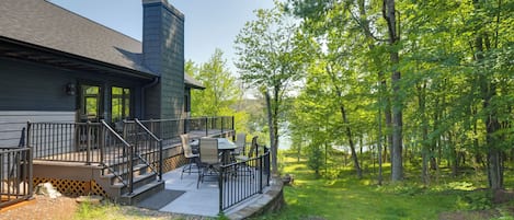 A house with a deck, outdoor furniture, and a view of a wooded area.
