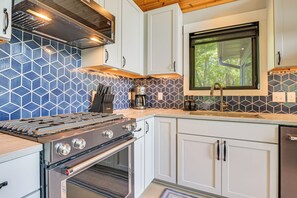 A modern kitchen with a gas stove, oven, and a coffee maker. - Gilmore Lake Family Escape w/ Game Room & Dock! (Minong)
