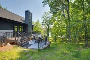 A house with a deck, outdoor furniture, and a view of a wooded area. - Gilmore Lake Family Escape w/ Game Room & Dock! (Minong)