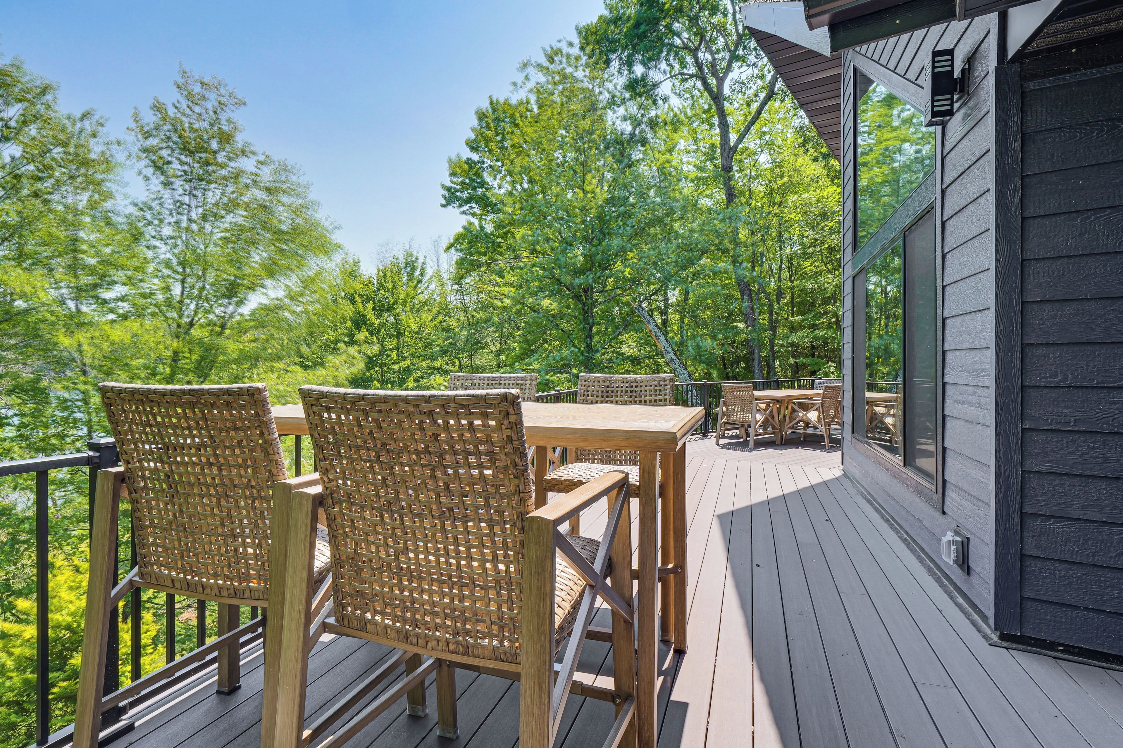 Une terrasse en bois, agrémentée de mobilier d’extérieur, entourée d’arbres.