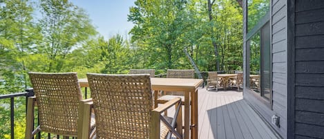 A wooden deck with outdoor furniture, surrounded by trees.