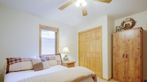 A bedroom with a bed, a nightstand, a lamp, a wardrobe, and a ceiling fan. - Lakefront Crystal Falls Home w/ Private Dock (Crystal Falls)