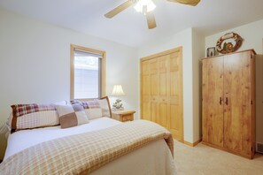 A bedroom with a bed, a nightstand, a lamp, a wardrobe, and a ceiling fan. - Lakefront Crystal Falls Home w/ Private Dock (Crystal Falls)