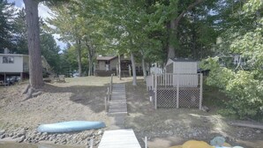 A wooden dock leading to a sandy beach area with a kayak and a paddleboard. - Lakefront Crystal Falls Home w/ Private Dock (Crystal Falls)