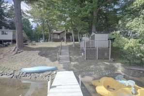 A wooden dock leading to a sandy beach area with a kayak and a paddleboard. - Lakefront Crystal Falls Home w/ Private Dock (Crystal Falls)