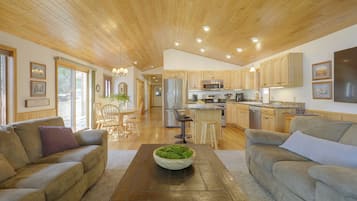 A spacious living room with a wooden coffee table, two sofas, and a kitchen in the background.