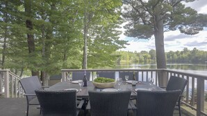 An outdoor dining area with a table set for four, surrounded by chairs, overlooking a lake. - Lakefront Crystal Falls Home w/ Private Dock (Crystal Falls)