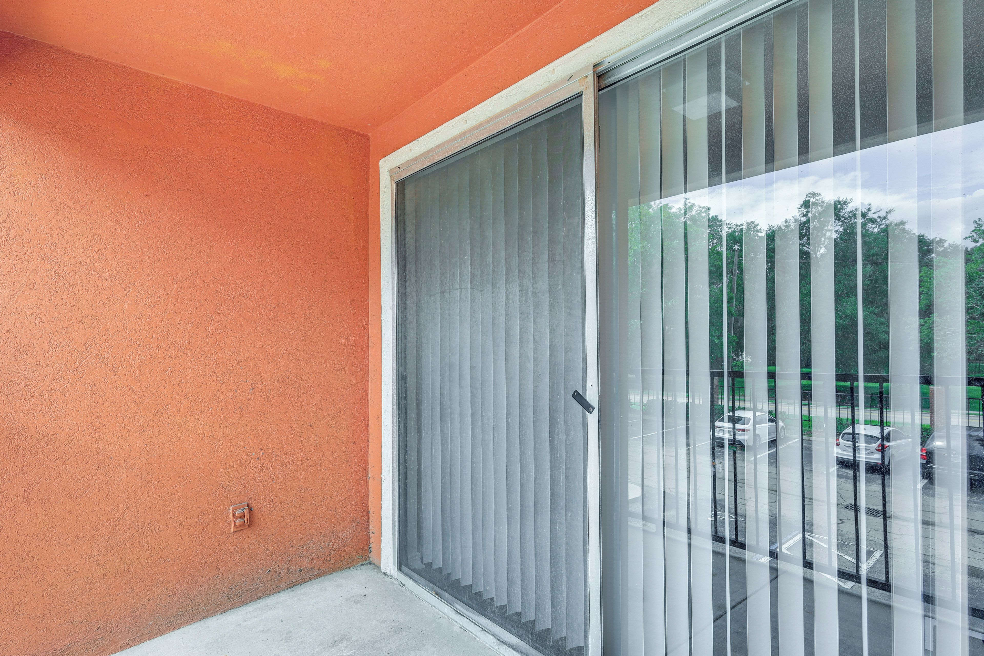 A room with a sliding glass door leading to a parking area.