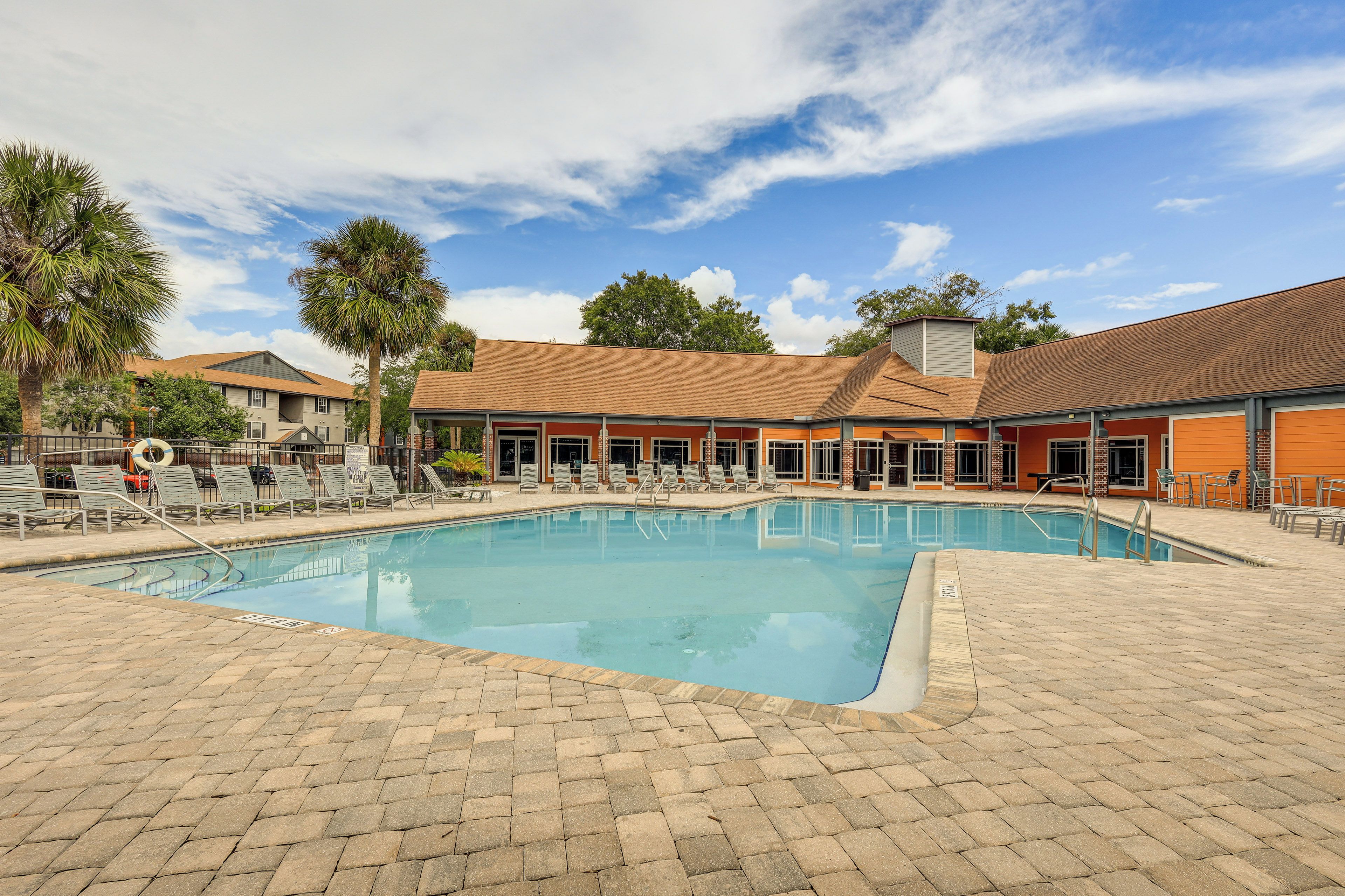 A swimming pool with lounge chairs and a brick patio.