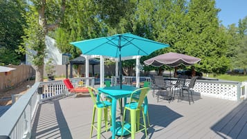 An outdoor patio with a table and chairs, surrounded by a white fence.