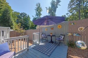 A deck with a checkered mat, two chairs, a table, and a purple umbrella. - Stylish & Spacious Home w/ Fenced Yard in Richmond (Richmond)