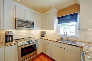 A kitchen with white cabinets, a stainless steel range, a microwave, a toaster, and a window with a view. - Stylish & Spacious Home w/ Fenced Yard in Richmond (Richmond)