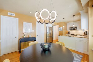 A modern kitchen with a central island, stainless steel appliances, and a dining area with a round table. - Stylish & Spacious Home w/ Fenced Yard in Richmond (Richmond)