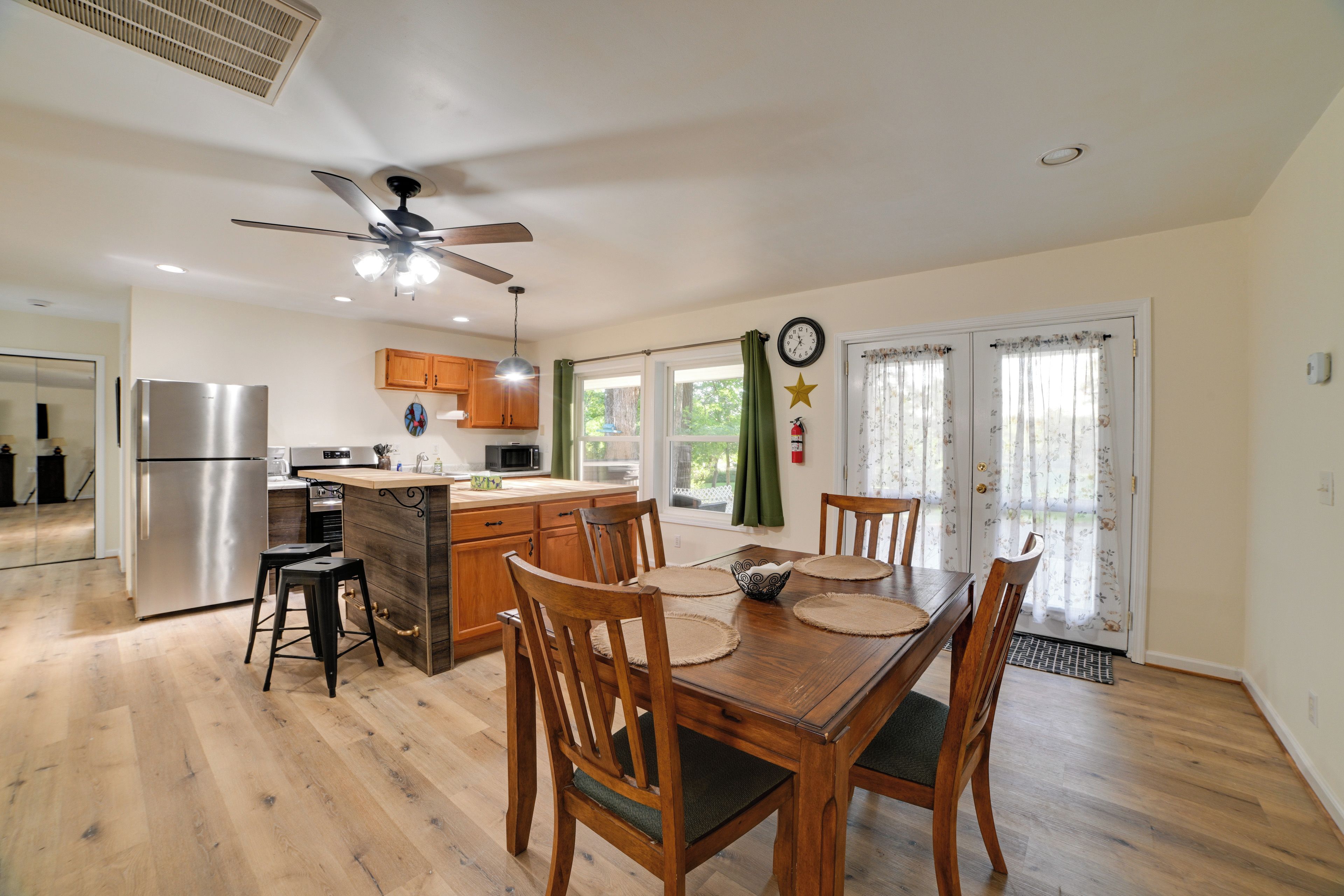 A modern kitchen with a central island, wooden chairs, and a dining table.