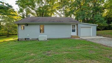 A single-story house with a garage, a satellite dish, and a small air conditioning unit.