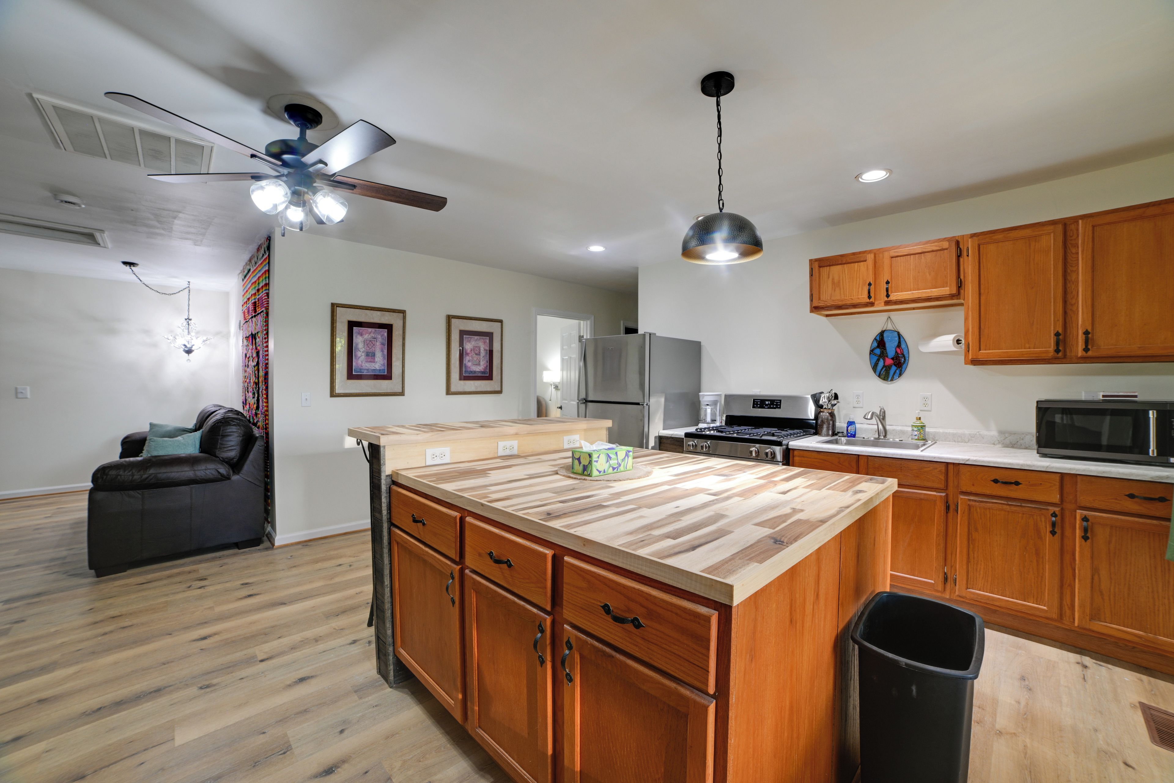 A modern kitchen with wooden cabinets, a central island, and a ceiling fan.