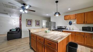 A modern kitchen with wooden cabinets, a central island, and a ceiling fan.