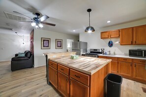 Une cuisine moderne avec des meubles en bois, un îlot central et un ventilateur de plafond.