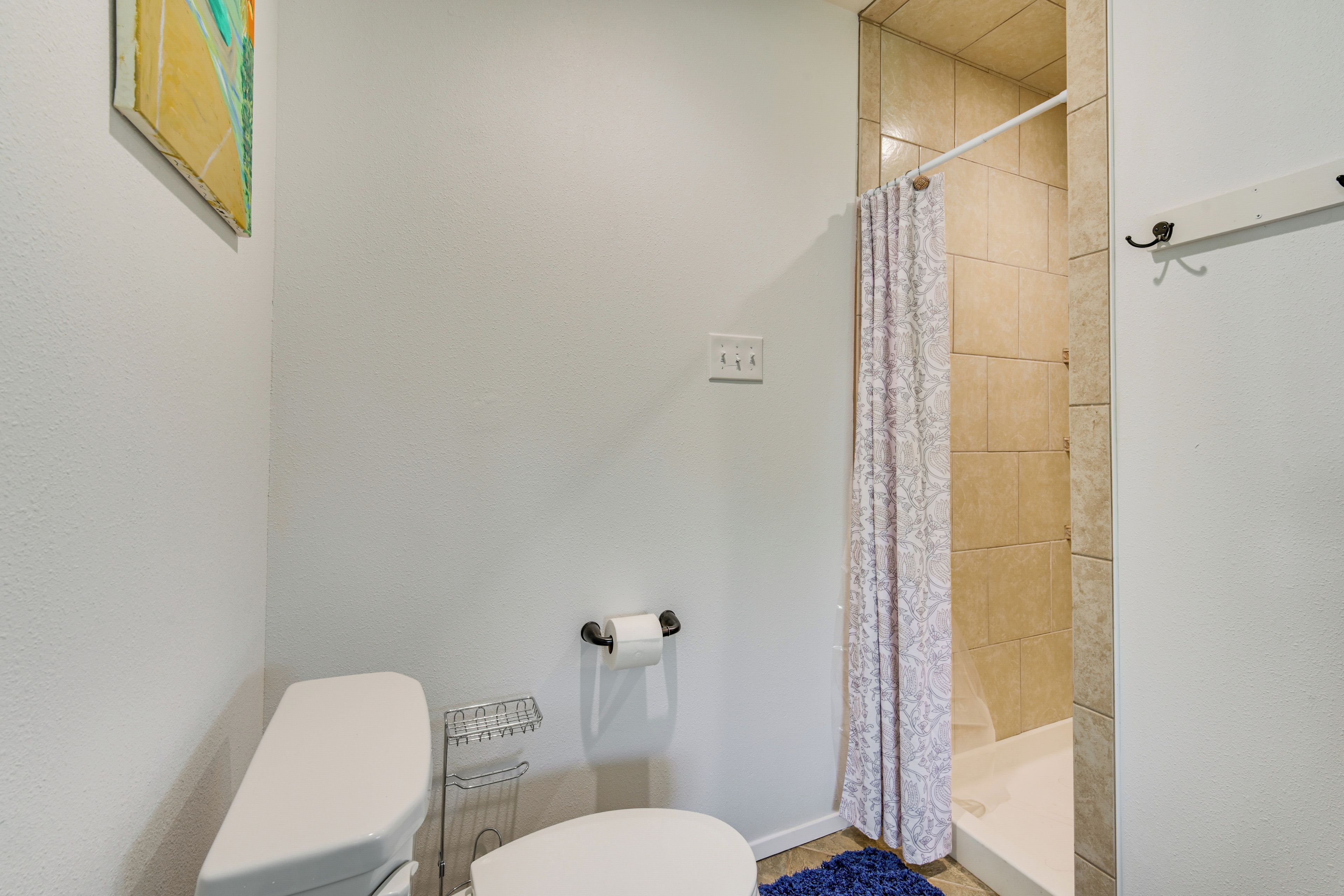 A bathroom with a toilet, shower, and a towel rack.