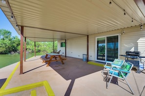 A covered patio area with a picnic table, chairs, and a grill.