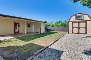 A single-story house with a covered porch, a fenced yard, and a gravel driveway.