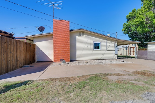 A single-story house with a brick chimney, a satellite dish, and a fenced yard.