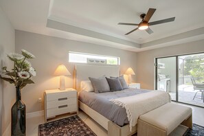 A bedroom with a bed, bedside lamps, a ceiling fan, a window, and a view of the outdoors. - Brand-new Luxury Home w/ Pool! 9 Mi to Pine Island (Cape Coral)