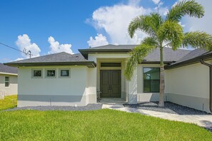 A two-story house with a front porch, a door, and a small patio area. - Brand-new Luxury Home w/ Pool! 9 Mi to Pine Island (Cape Coral)