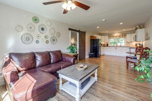 A living room with a brown leather sofa, a coffee table, and a ceiling fan.