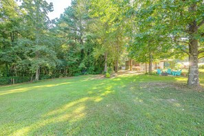 A well-maintained grassy area with trees, a fenced area, and outdoor seating. - Fire Pit + Yard: Peaceful Nottoway County Apt (Blackstone)