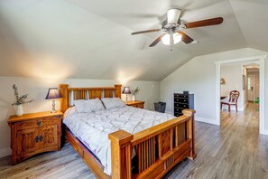 Un dormitorio con una cama de madera, dos mesitas de noche, un ventilador de techo y una mesita de noche con una lámpara.