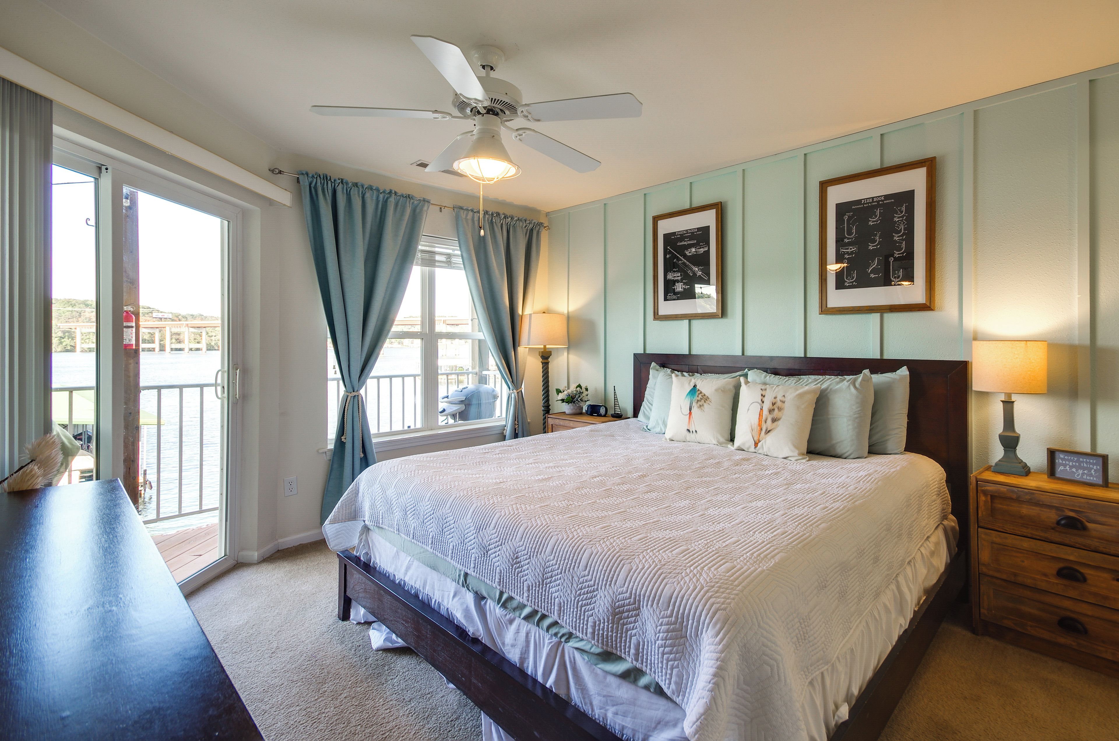 A bedroom with a bed, a nightstand, a lamp, a ceiling fan, and a window with curtains.