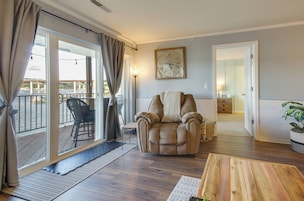 Amplia sala de estar con un sillón de cuero, una mesa de centro de madera y vistas a un balcón con una silla.