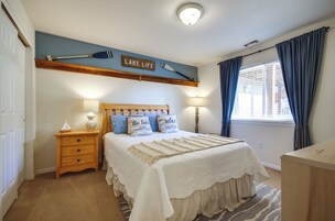 Un dormitorio con cama, mesitas de noche, lámpara, ventana con cortinas y un cartel en la pared.