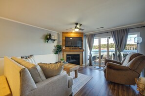 Een woonkamer met een open haard, een plafondventilator en uitzicht op de omgeving.