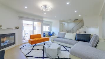 Uma sala de estar moderna com lareira, sofá, mesa de centro e escada.