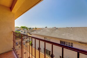 A balcony with a view of a residential area, including houses and a large flat roof structure. - Extended Stay Near Beaches & LA Commuter Routes (Torrance)