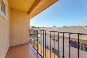 A balcony with a view of a residential area, a tiled floor, and a metal railing. - Extended Stay Near Beaches & LA Commuter Routes (Torrance)