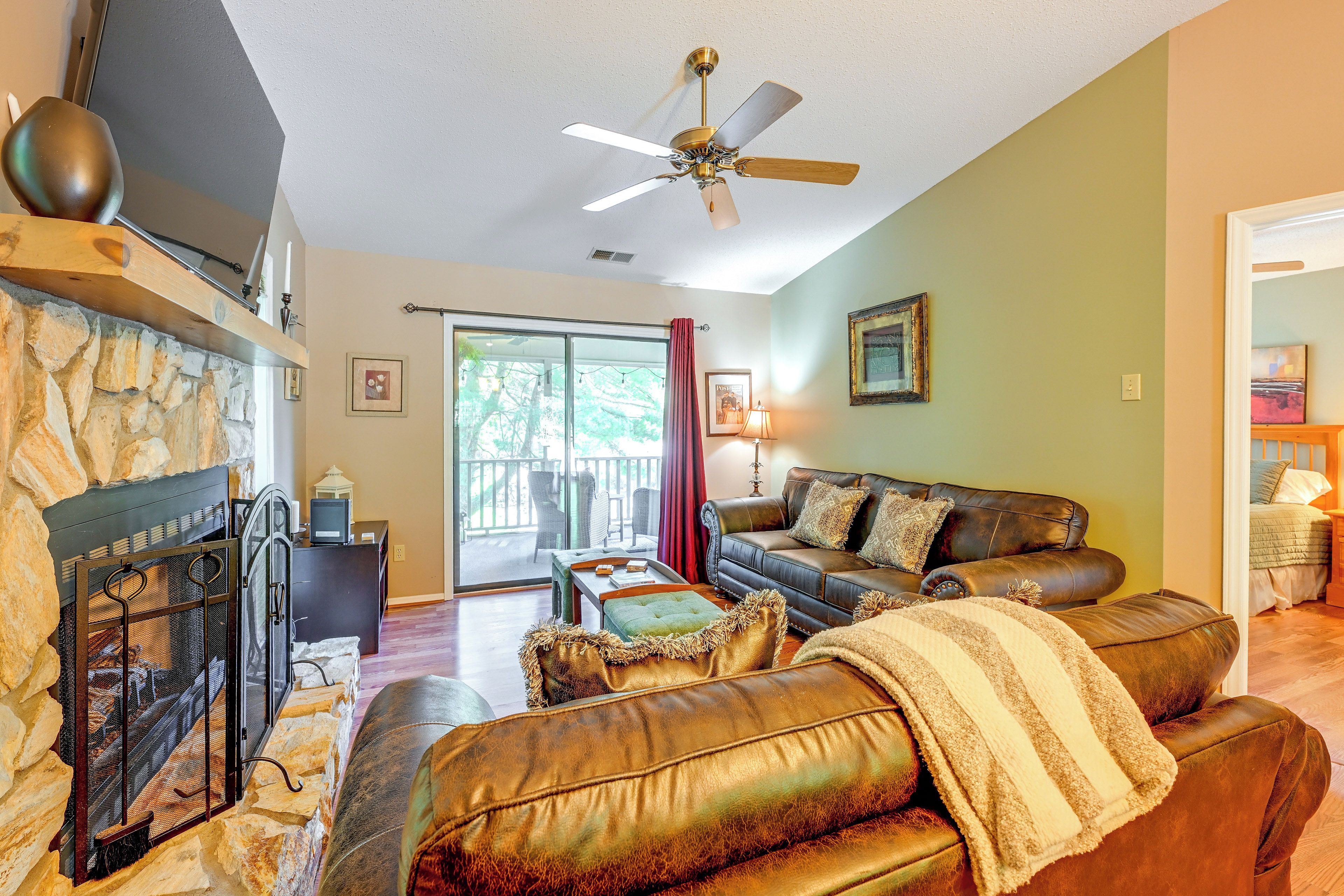 A living room with a fireplace, leather sofa, and a ceiling fan.