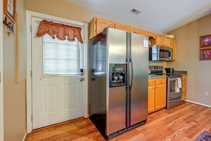 A compact kitchen with a refrigerator, microwave, oven, and a small countertop area.