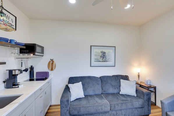 A compact living space with a kitchenette, grey sofa, and a framed artwork on the wall. - Trail Access & Views! 90-acre Haven in Hot Springs (Hot Springs)