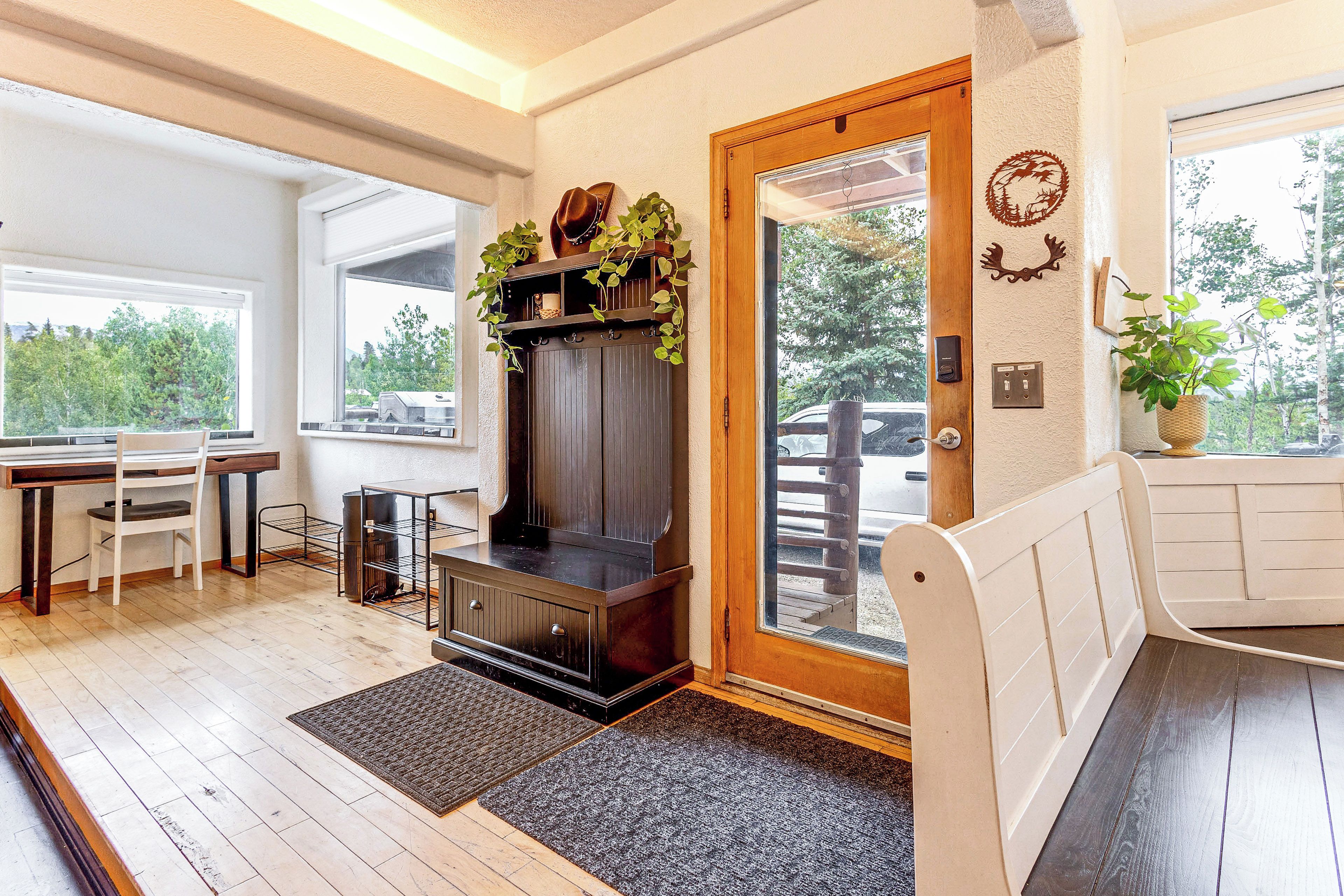 A room with a wooden bench, a fireplace, a dining table with chairs, and a view of the outdoors.
